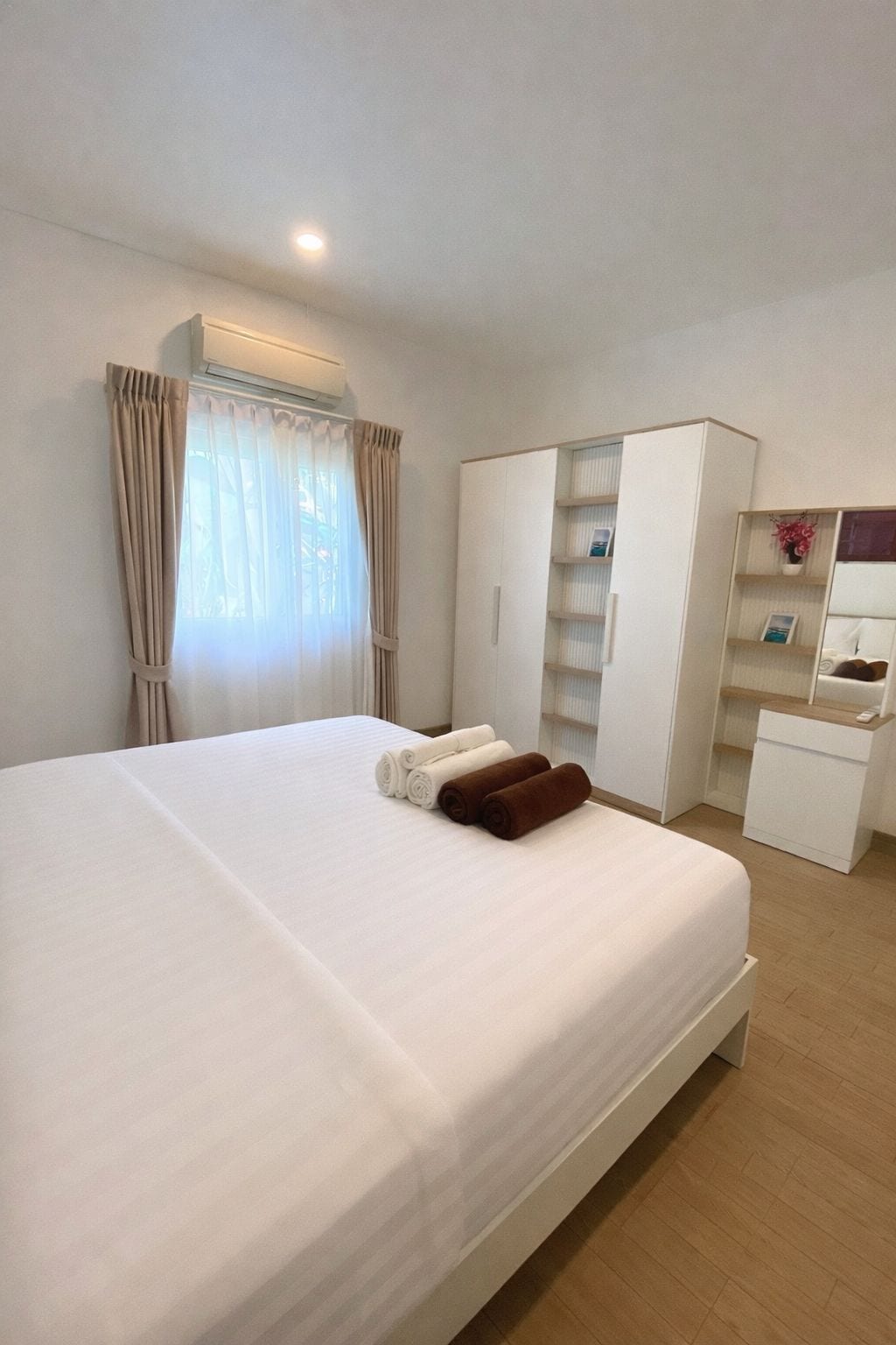 A hotel room with a bed, a wardrobe, a desk, and a mirror.