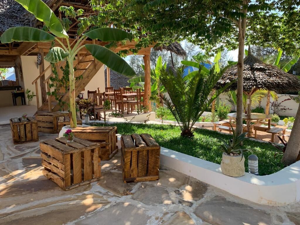 Eine Terrasse im Freien mit Holzmöbeln und einem strohgedeckten Bauwerk.
