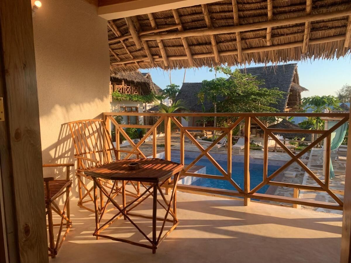 A wooden deck with a table and chairs overlooking a pool.
