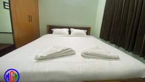 A hotel room with a large bed, wooden headboard, and a wardrobe. - MGM Suite Rooms (Tiruvannamalai)