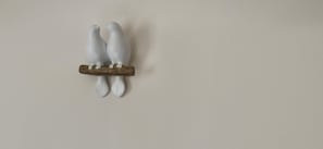 A wall-mounted sculpture of two white birds perched on a branch. - ANGEL'S (Angles)