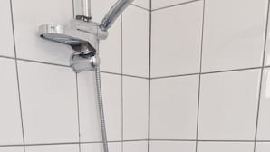 En dusch med ett duschmunstycke som kan hållas i handen och en väggmonterad blandare.
