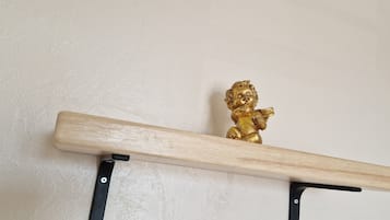 A wooden shelf with a golden figurine against a plain wall.