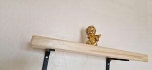A wooden shelf with a golden figurine against a plain wall. - ANGEL'S (Angles)