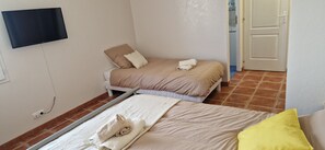 A bedroom with a bed, a TV mounted on the wall, and a door leading to another room. - ANGEL'S (Angles)