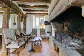 A rustic interior with wooden beams, a stone fireplace, and traditional furniture.