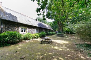 A stone building with a picnic table in a garden.