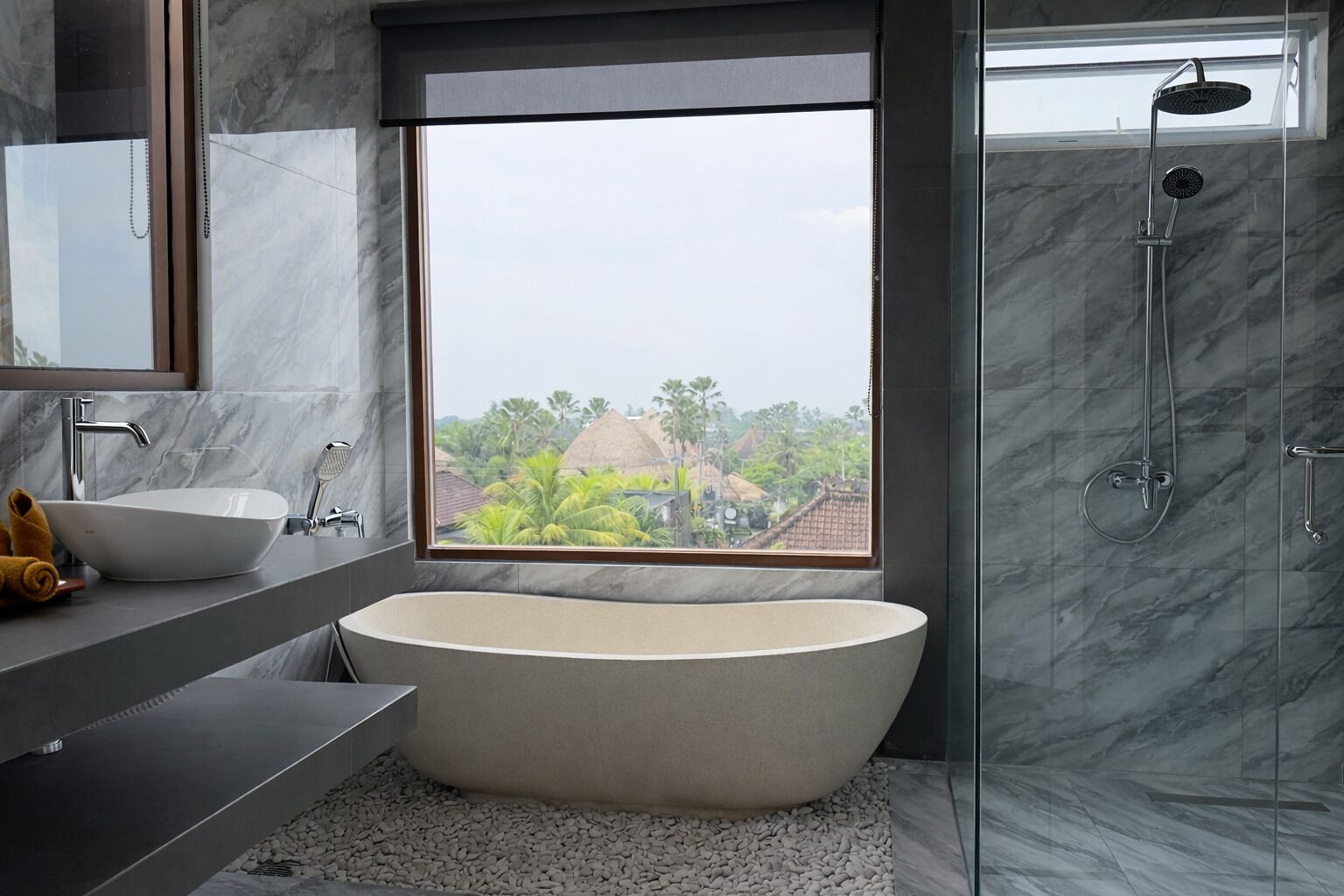 A modern bathroom with a freestanding bathtub, a large window with a view of greenery and buildings, and a separate shower area.
