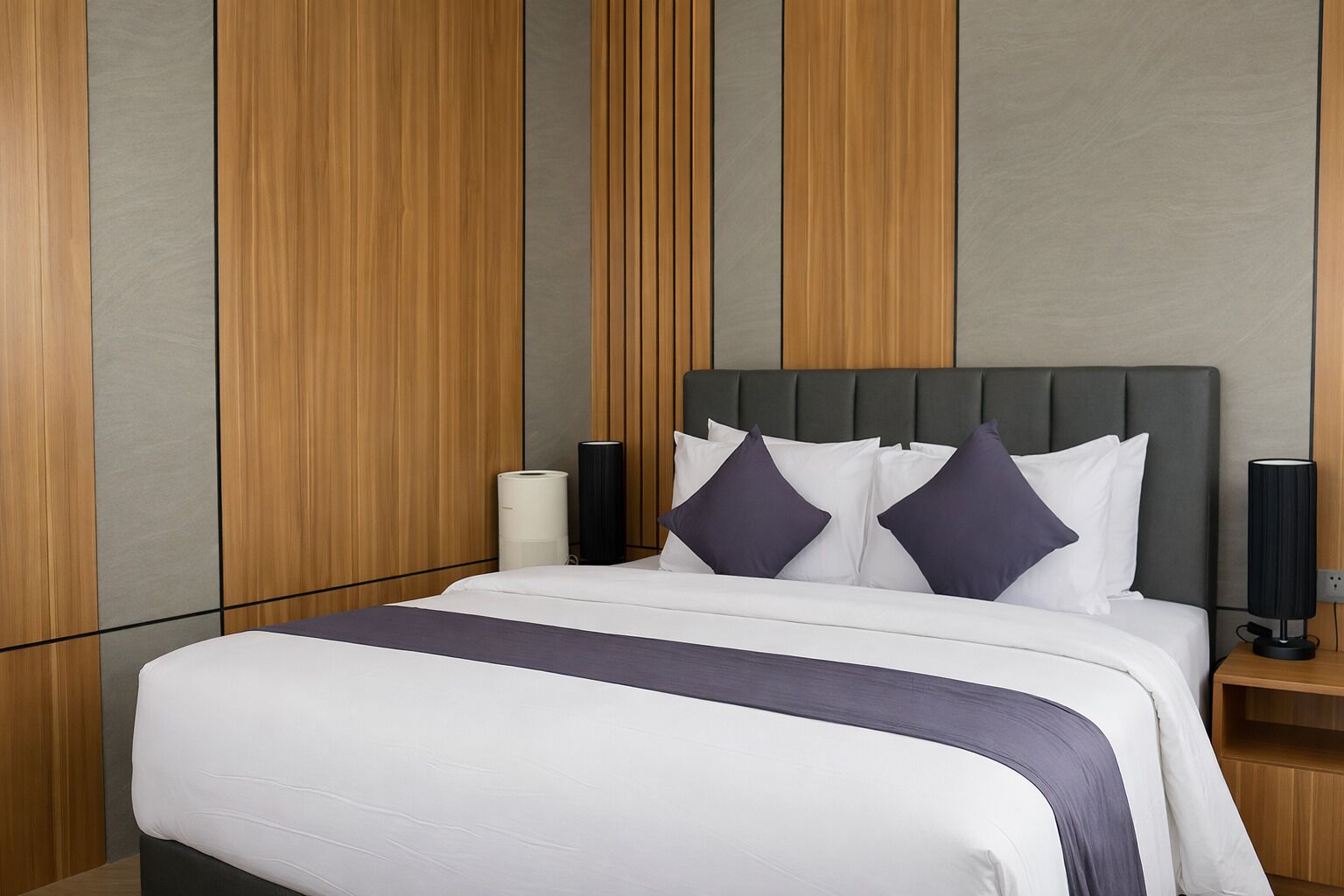 A modern hotel room with a large bed, grey and wooden panel walls, and two bedside lamps.