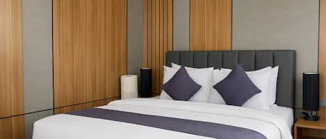 A modern hotel room with a large bed, grey and wooden panel walls, and two bedside lamps.