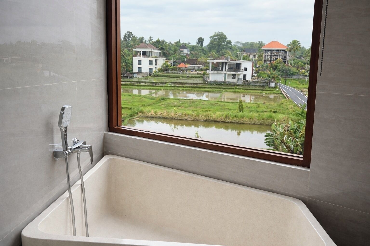 A bathroom with a bathtub, a window, and a view of a water body and buildings.