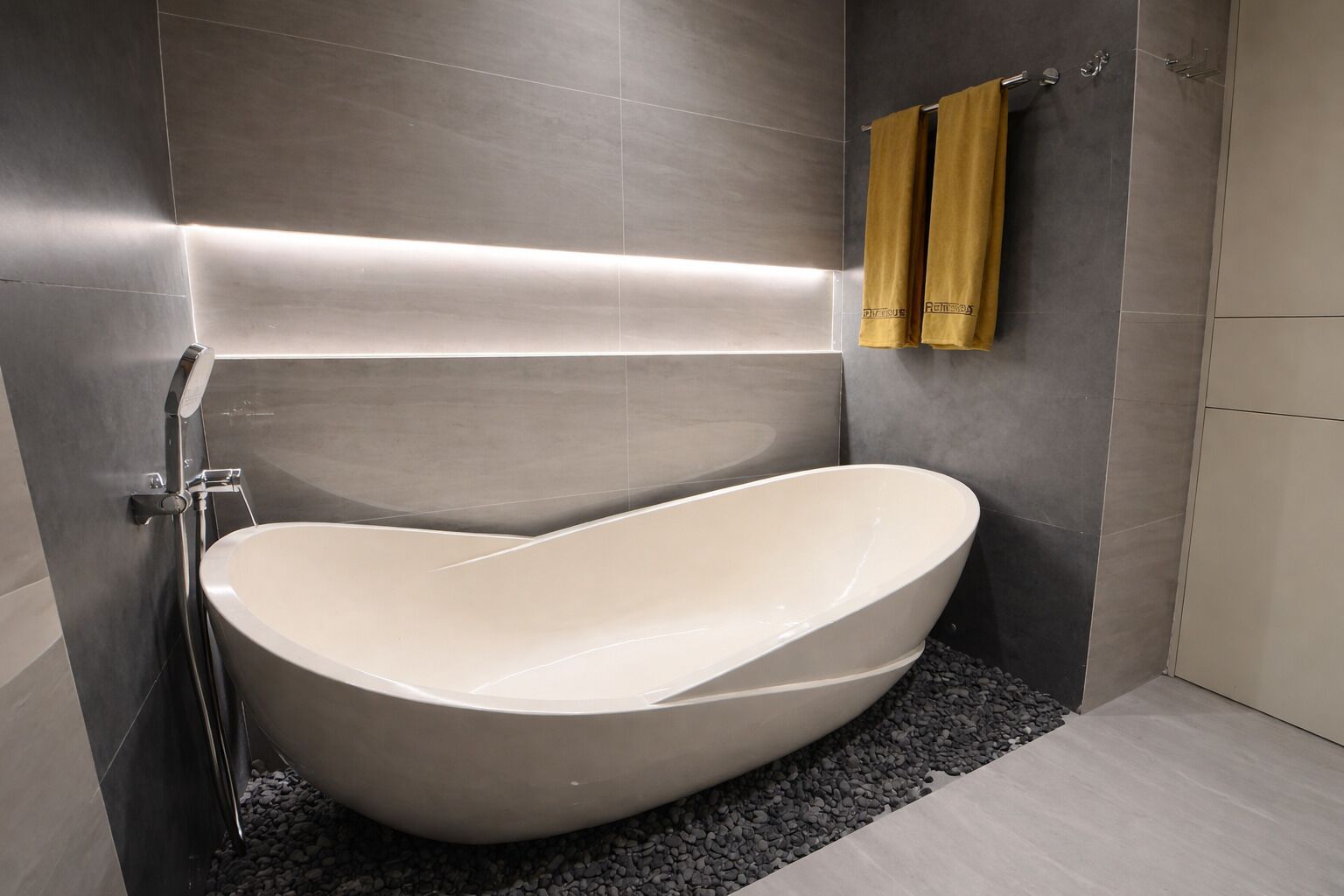 A modern bathroom with a freestanding bathtub, a towel rack with towels, and a sleek, minimalist design.