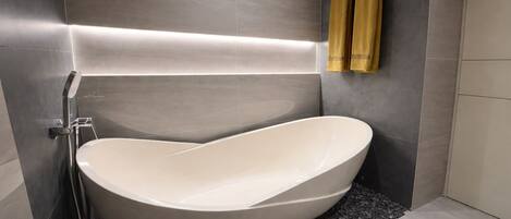 A modern bathroom with a freestanding bathtub, a towel rack with towels, and a sleek, minimalist design.