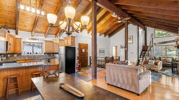 Un vaste espace de vie comprenant un grand canapé, un plancher en bois et une cuisine dotée de meubles en bois et d’un îlot central.