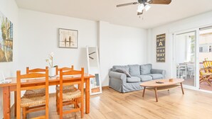 Ett modernt vardagsrum med ett matbord, stolar, en soffa och en takfläkt.