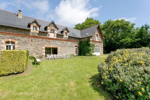 A stone building with a large lawn, outdoor seating, and a well-maintained garden.
