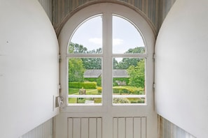 A white arched doorway with a view of a garden and a building in the background.