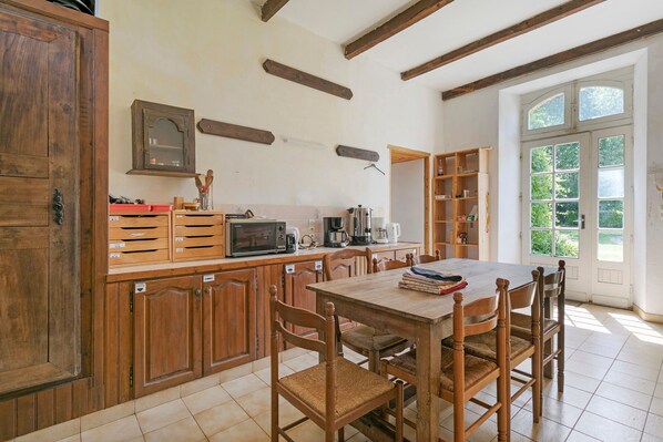 A kitchen with wooden cabinets, a dining table, chairs, a microwave, and a coffee maker.