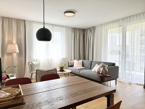 A modern living room with a wooden dining table, grey sofa, and a round coffee table. - 70m2 Apartment near Kirschblütenpark - UNO-City - Vienna International School (Wien)