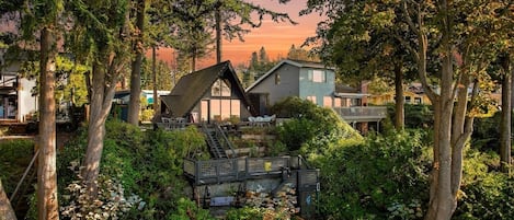 Um bairro residencial com uma casa, apresentando telhado inclinado e escada que dá para um deck.