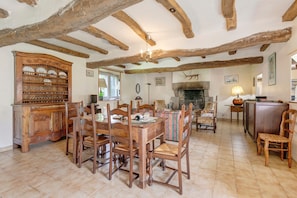 A rustic dining area with a wooden table and chairs, a large wooden cabinet, and a fireplace.