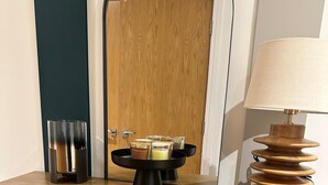 A wooden counter with a black tray holding several glasses, a lamp, and a glass container. - Luxury two bed two Bath In Excel (London)