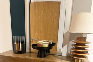 A wooden counter with a black tray holding several glasses, a lamp, and a glass container. - Luxury two bed two Bath In Excel (London)