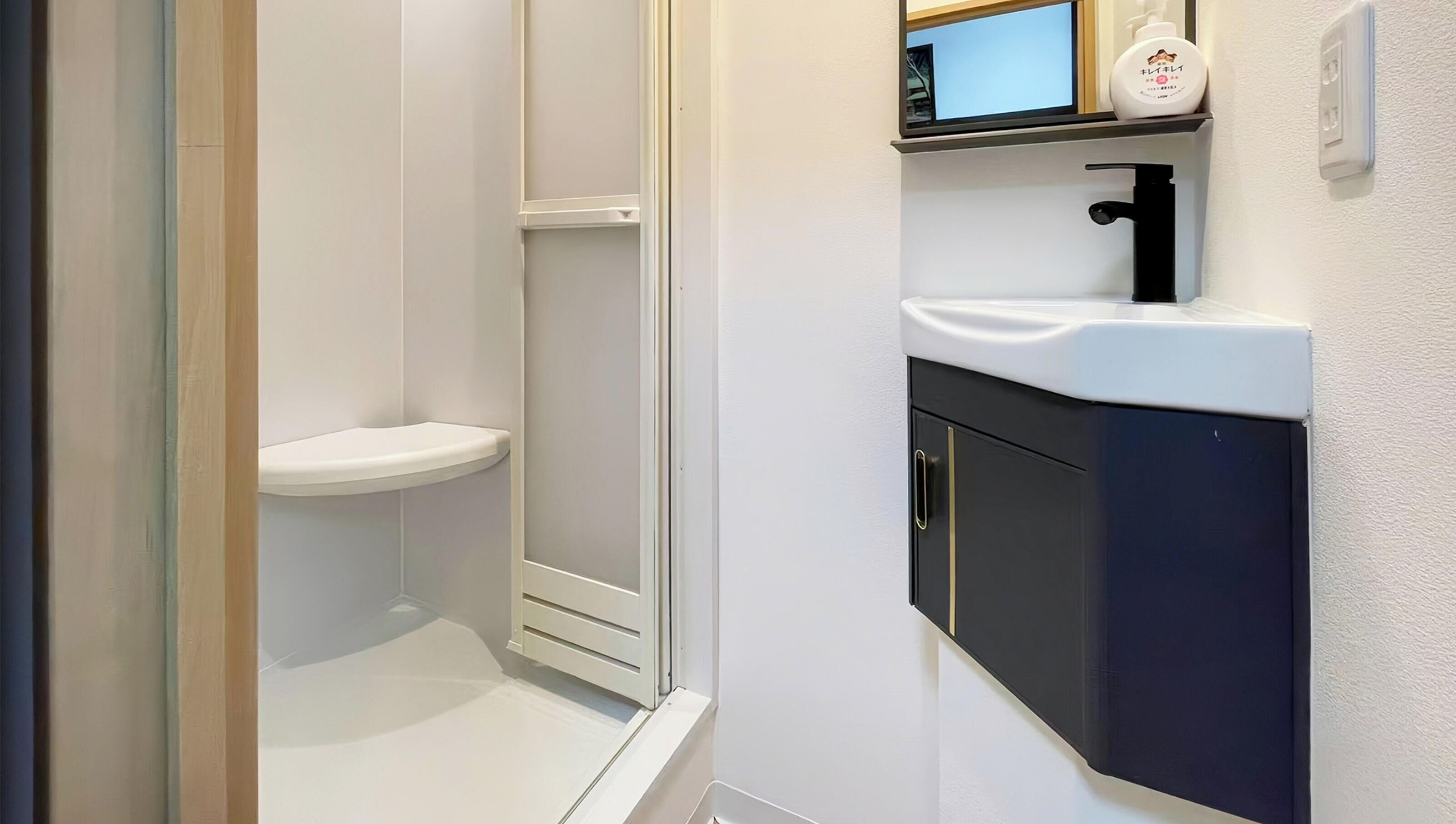 A bathroom with a white toilet, a shower enclosure, and a sink with a black cabinet.