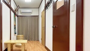 A hallway with wooden flooring, a table, a chair, and a woven mat.