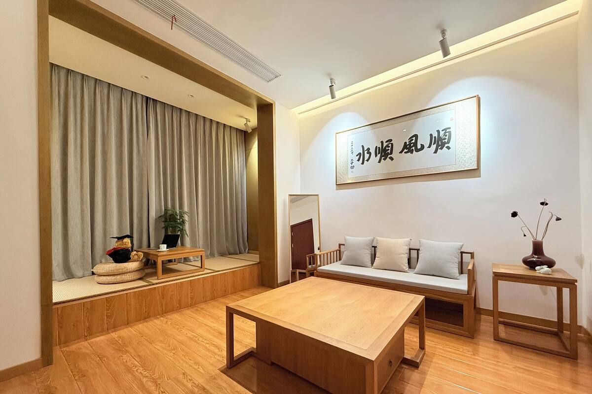 A modern living room with a wooden floor, a sofa, a coffee table, and a wall-mounted artwork.