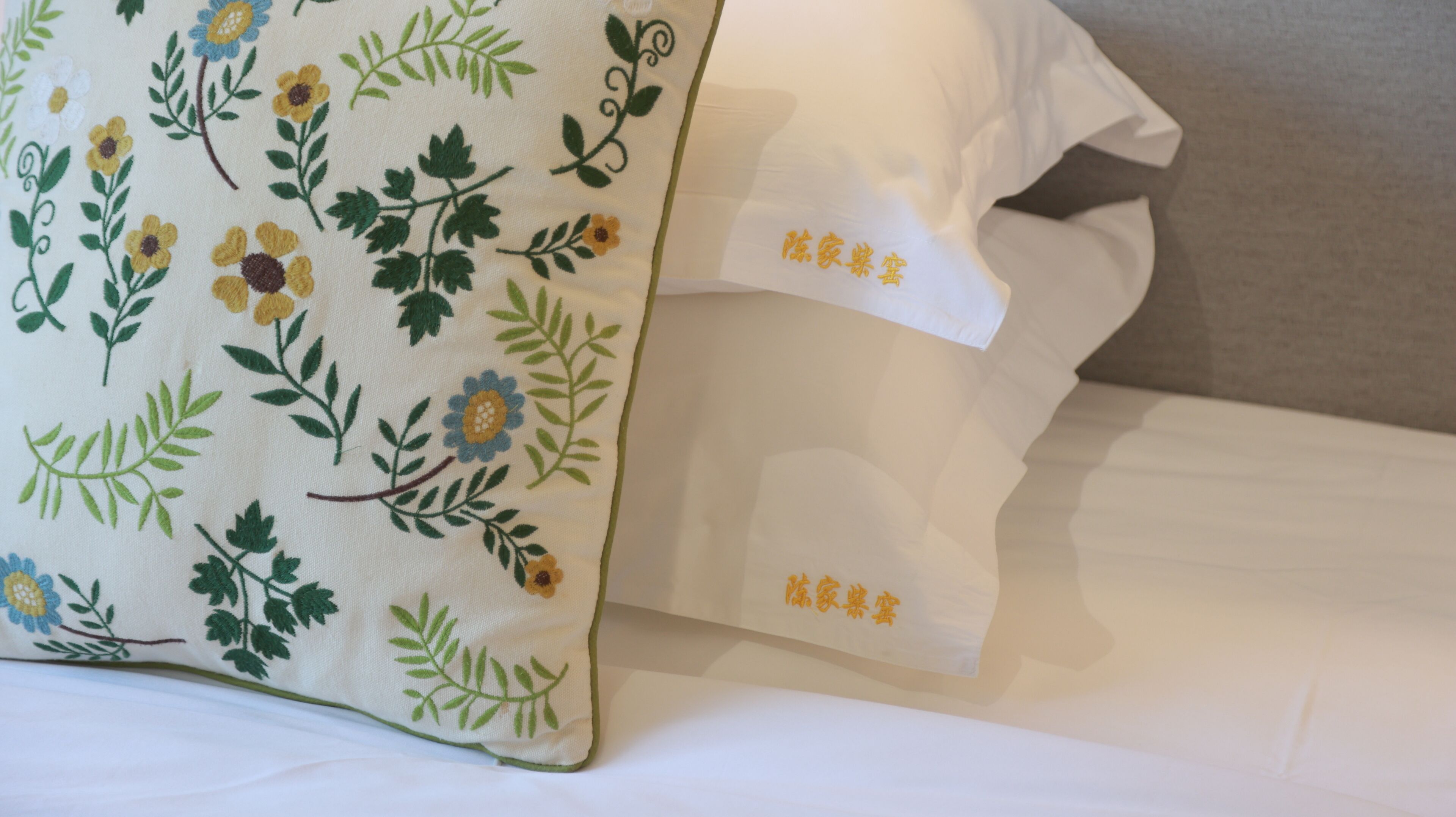 A pillow with floral embroidery and a tag with Chinese characters.