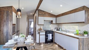 A modern kitchen with white cabinets, a wooden ceiling, and a dining area with a table set for four. - 2 bedroom accommodation in Bishop Auckland (Bishop Auckland)