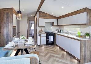 Eine moderne Küche mit weißen Schränken, einer Holzbalkendecke und einem Essbereich mit Tisch für vier Personen.