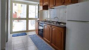 A kitchen with wooden cabinets, a white refrigerator, a stove, and a sink. - Studio apartment in downtown (Realmonte)