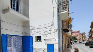 A narrow urban street with buildings featuring balconies and blue doors. - Studio apartment in downtown (Realmonte)