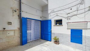 A narrow alleyway with two blue doors, a small potted plant, and a utility box. - Studio apartment in downtown (Realmonte)