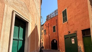 Une rue étroite, bordée de bâtiments des deux côtés, avec une porte verte et un panneau indiquant qu’il est interdit de se garer.