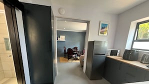 Eine moderne Küche mit Kühlschrank, Mikrowelle und Kaffeemaschine. Ein Essbereich mit Tisch und Stühlen ist ebenfalls vorhanden.