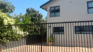 Ein modernes, zweistöckiges Haus mit flachem Dach, einem Pflasterweg aus Ziegelsteinen und einem Metallzaun.