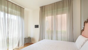 Una camera da letto con un letto grande, tende leggere, un comodino e un tavolino.
