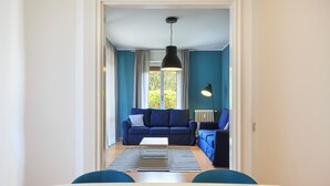 Un soggiorno con un divano blu, un tavolino da caffè bianco e un tappeto a righe.