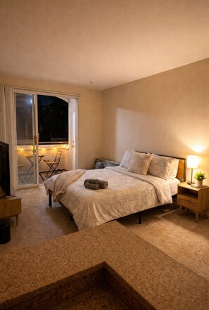 A bedroom with a bed, a nightstand, a lamp, and a sliding glass door leading to an outdoor area with a table and chairs. - Cozy 1BA Marina Del Rey Venice (Marina del Rey)