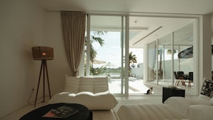 A modern living room with a white sofa, a black coffee table, and a floor lamp. - The Iggy (Cemagi)