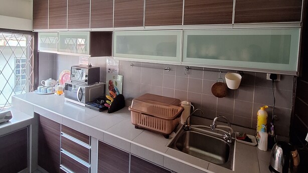 A modern kitchen with dark wooden cabinets, a white countertop, a built-in microwave, and a sink. - Spacious 4-bedroom house in gorgeous Subang Jaya with AC (Subang Jaya)