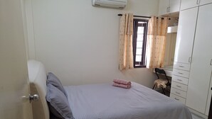 A bedroom with a bed, a wardrobe, a window with curtains, and an air conditioning unit. - Spacious 4-bedroom house in gorgeous Subang Jaya with AC (Subang Jaya)