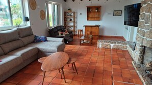 A living room with a sofa, a wooden coffee table, and a stone fireplace. - Unique Large Home in Estoril with Pool - Perfect for Families (Estoril)