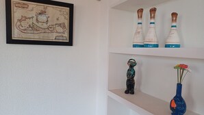 A framed map on the wall, three decorative vases on the top shelf, a small figurine on the middle shelf, and a vase with a flower on the bottom shelf. - Unique Large Home in Estoril with Pool - Perfect for Families (Estoril)