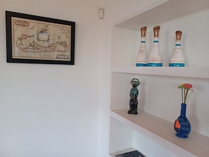 A framed map on the wall, three decorative vases on the top shelf, a small figurine on the middle shelf, and a vase with a flower on the bottom shelf. - Unique Large Home in Estoril with Pool - Perfect for Families (Estoril)
