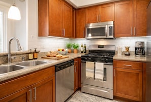 A modern kitchen with wooden cabinets, stainless steel appliances, a granite countertop, and a built-in dishwasher. - Cozy 1-bedroom apartment with AC in tranquil Marina del Rey Elegant (Marina del Rey)