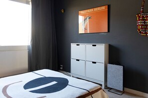 Une chambre d’hôtel avec un lit, une armoire, un radiateur et une affiche au mur.